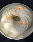 A luxurious 3-wick candle called, Serene, on a concrete Ripple tray. The candle is a twisted cable-wire shape and measures about 9 in in diameter, 2.5 inches in height and weighs 52 ounces.