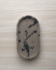 Concrete trinket tray in wenge with abstract off-black color accents.