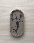 Concrete trinket tray in wenge with abstract off-black color accents.