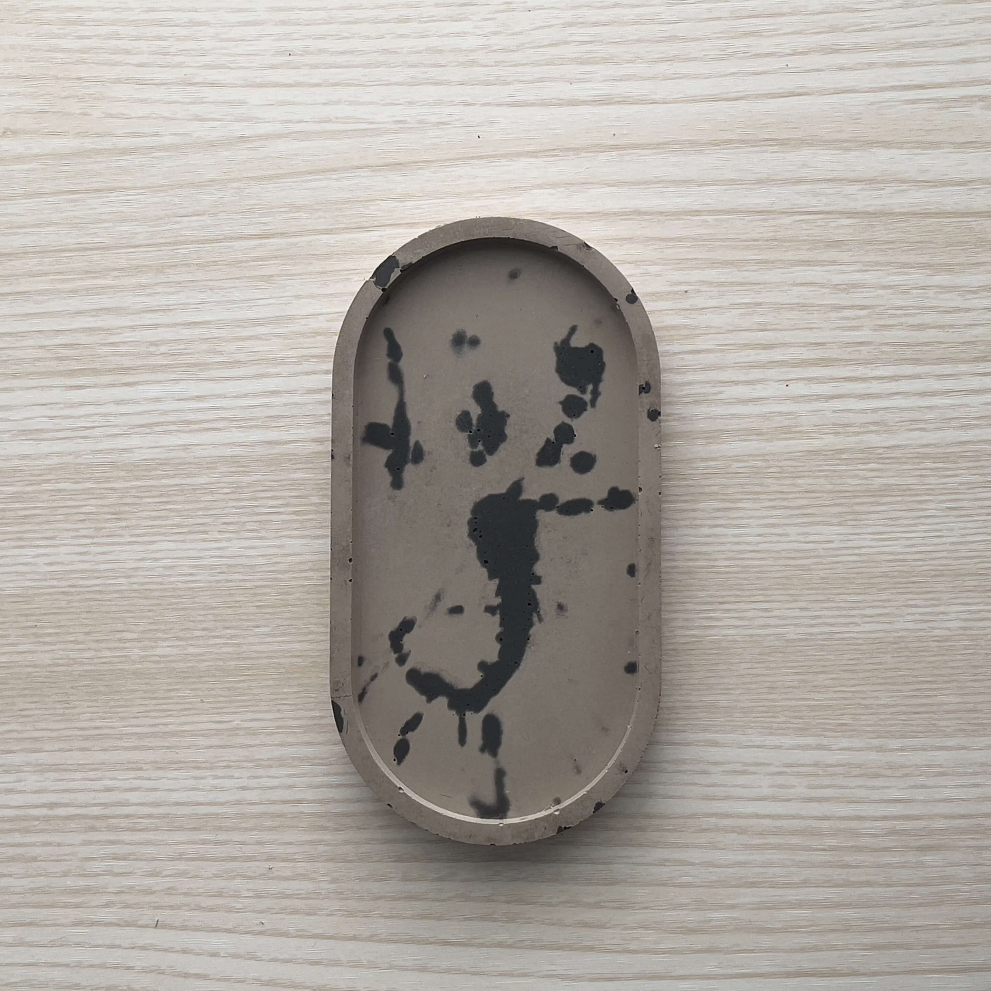 Concrete trinket tray in wenge with abstract off-black color accents. 