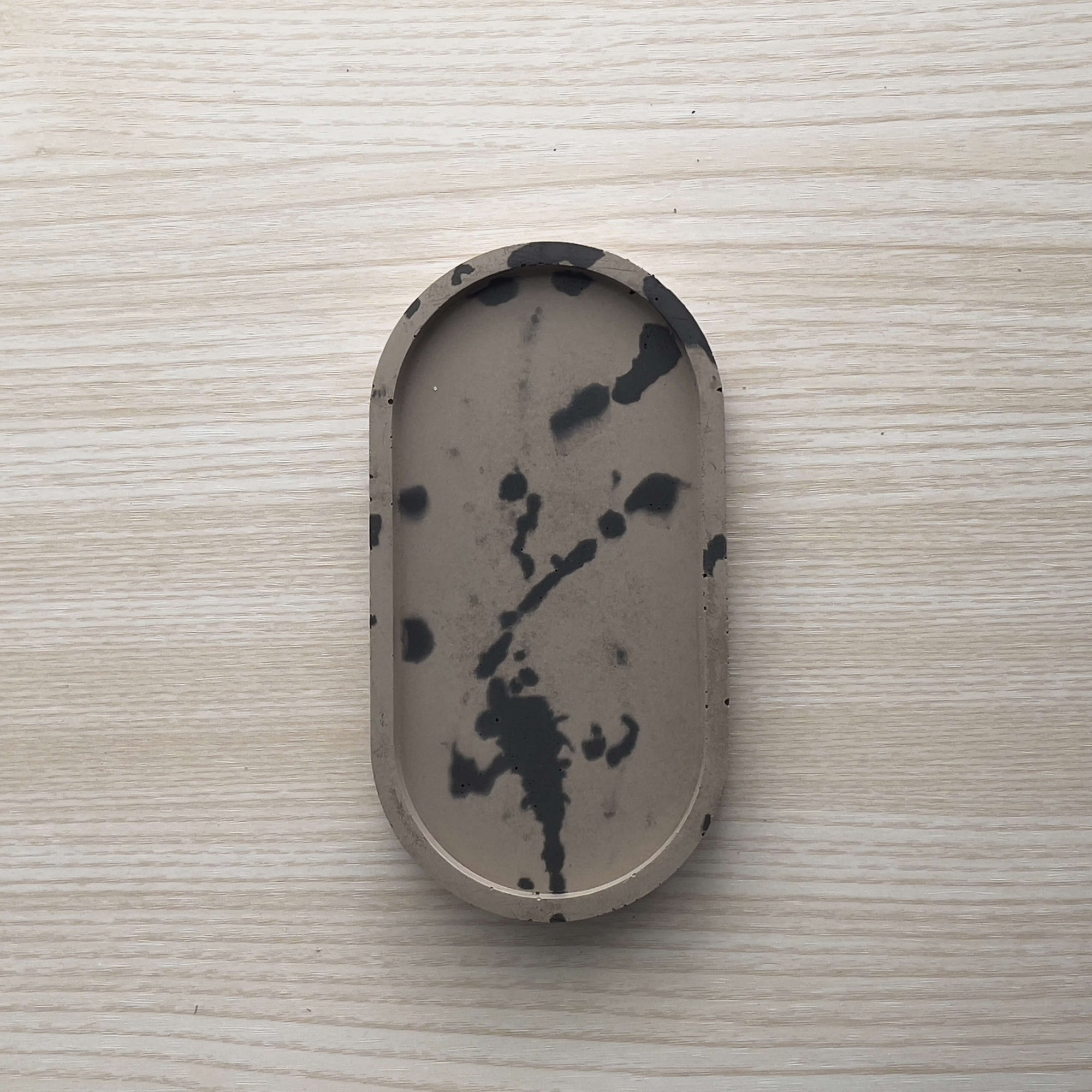 Concrete trinket tray in wenge with abstract off-black color accents. 