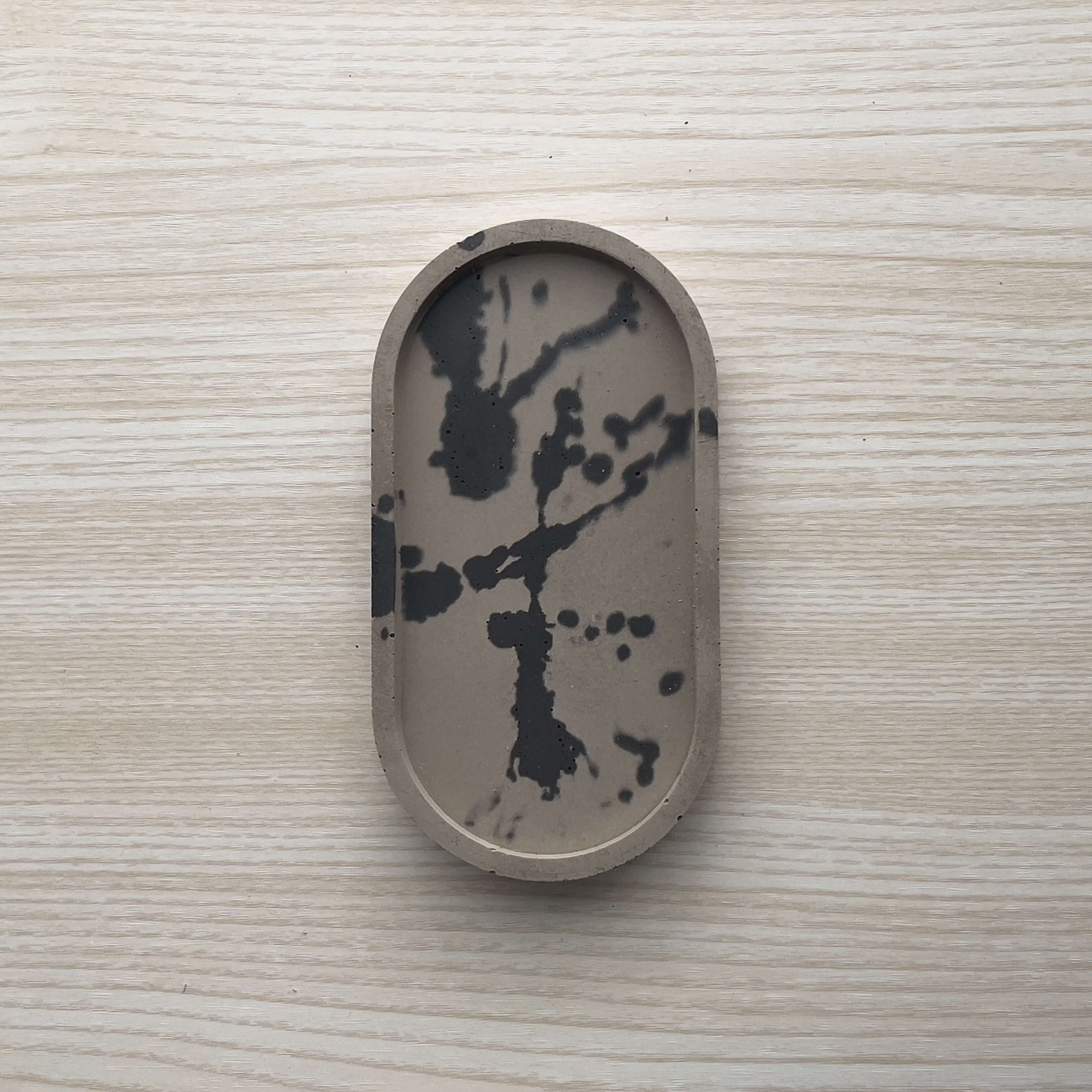 Concrete trinket tray in wenge with abstract off-black color accents. 