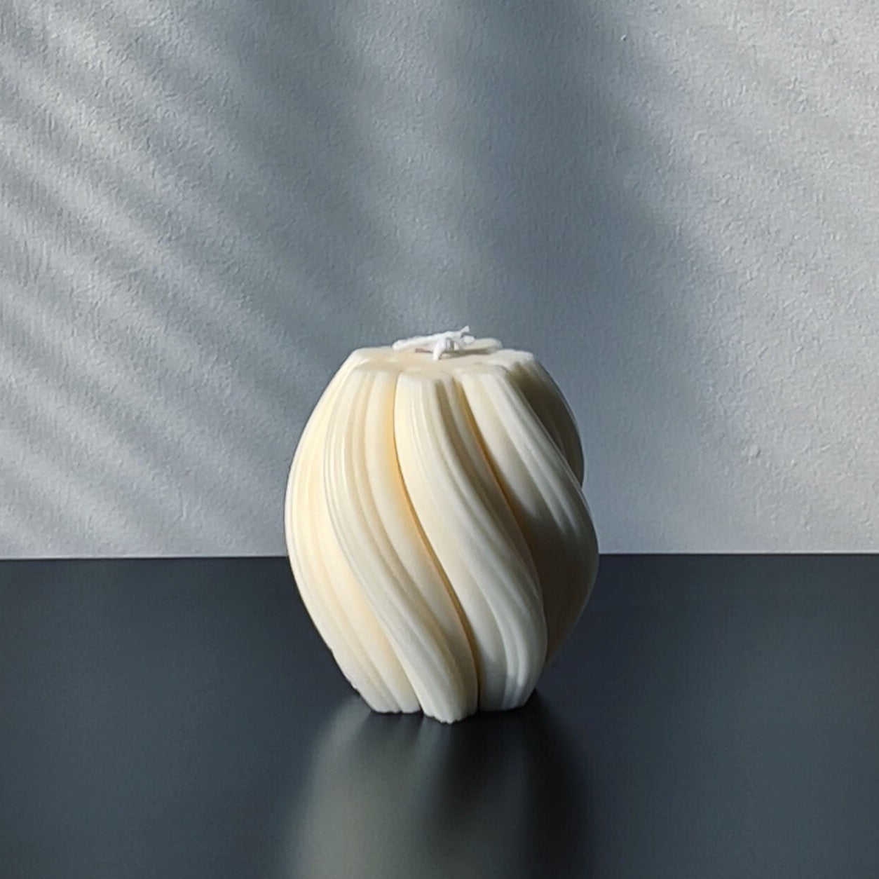 Nev sculptural candle with ribbed swirl textural design.